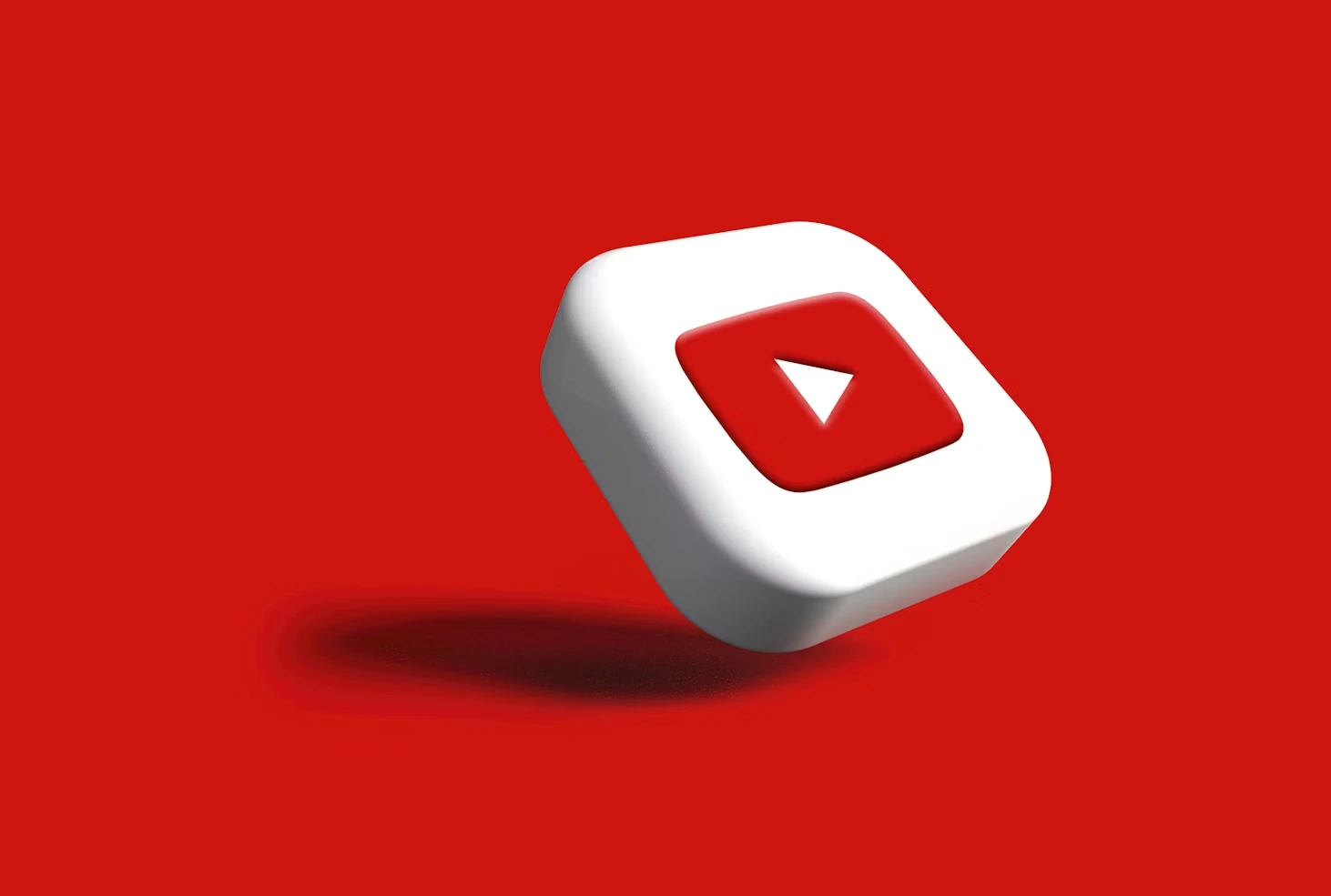 Ícono tridimensional del botón de reproducción de YouTube flotando sobre un fondo rojo sólido, con sombra suave que aporta profundidad visual.